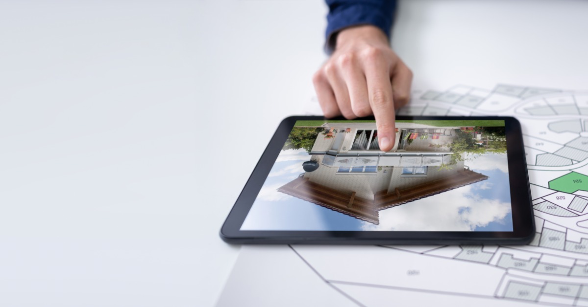 A professional leans over a table in an office to look at a laptop screen that an employee gestures toward.